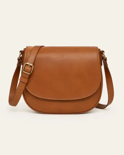Borsa a sella in pelle color cognac su fondo avorio