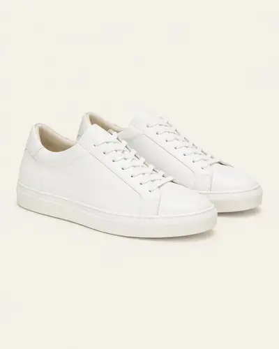 Sneakers bianche minimal in pelle su fondo avorio